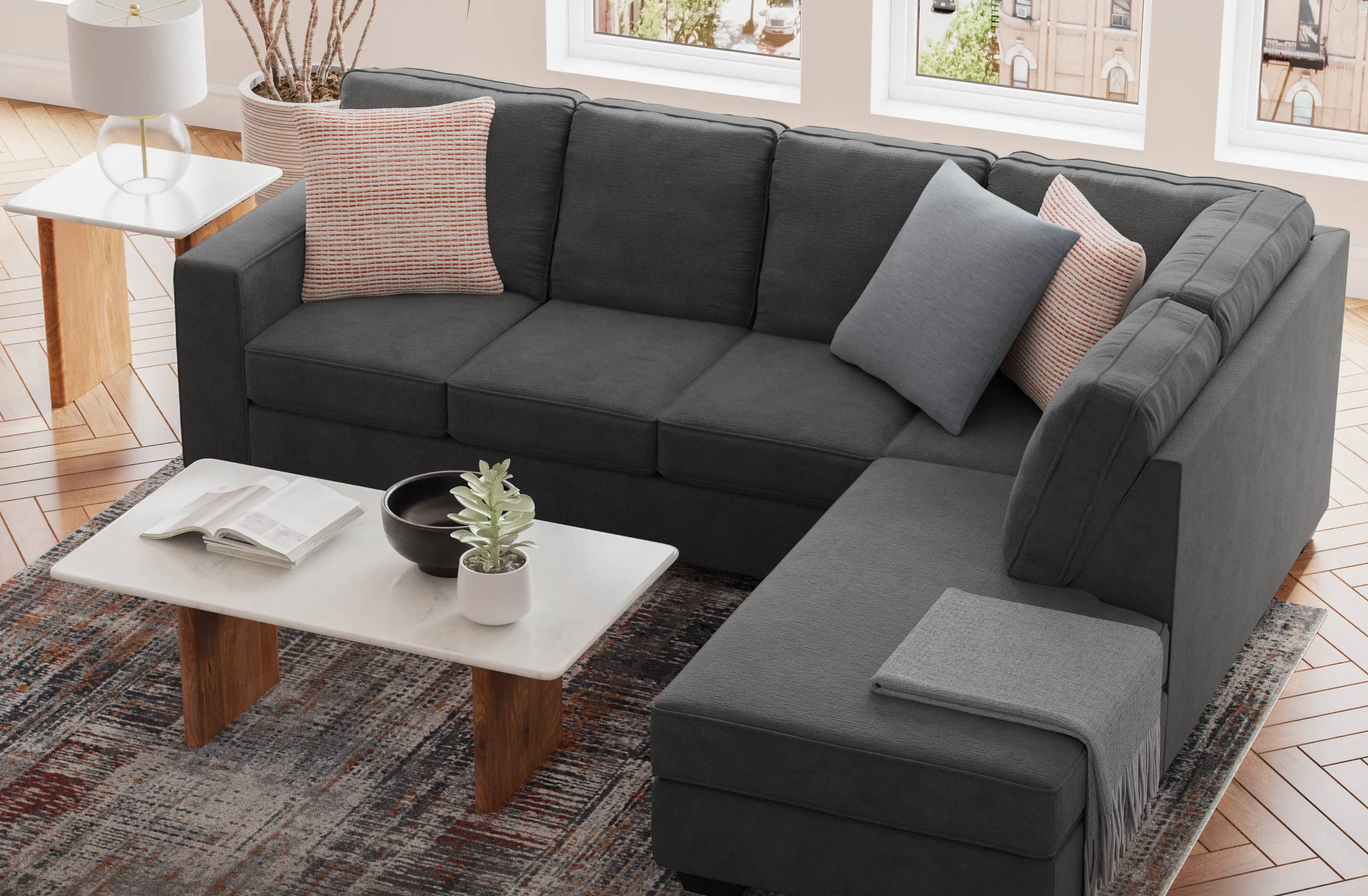 A modern gray sectional sofa with decorative pillows and a coffee table.