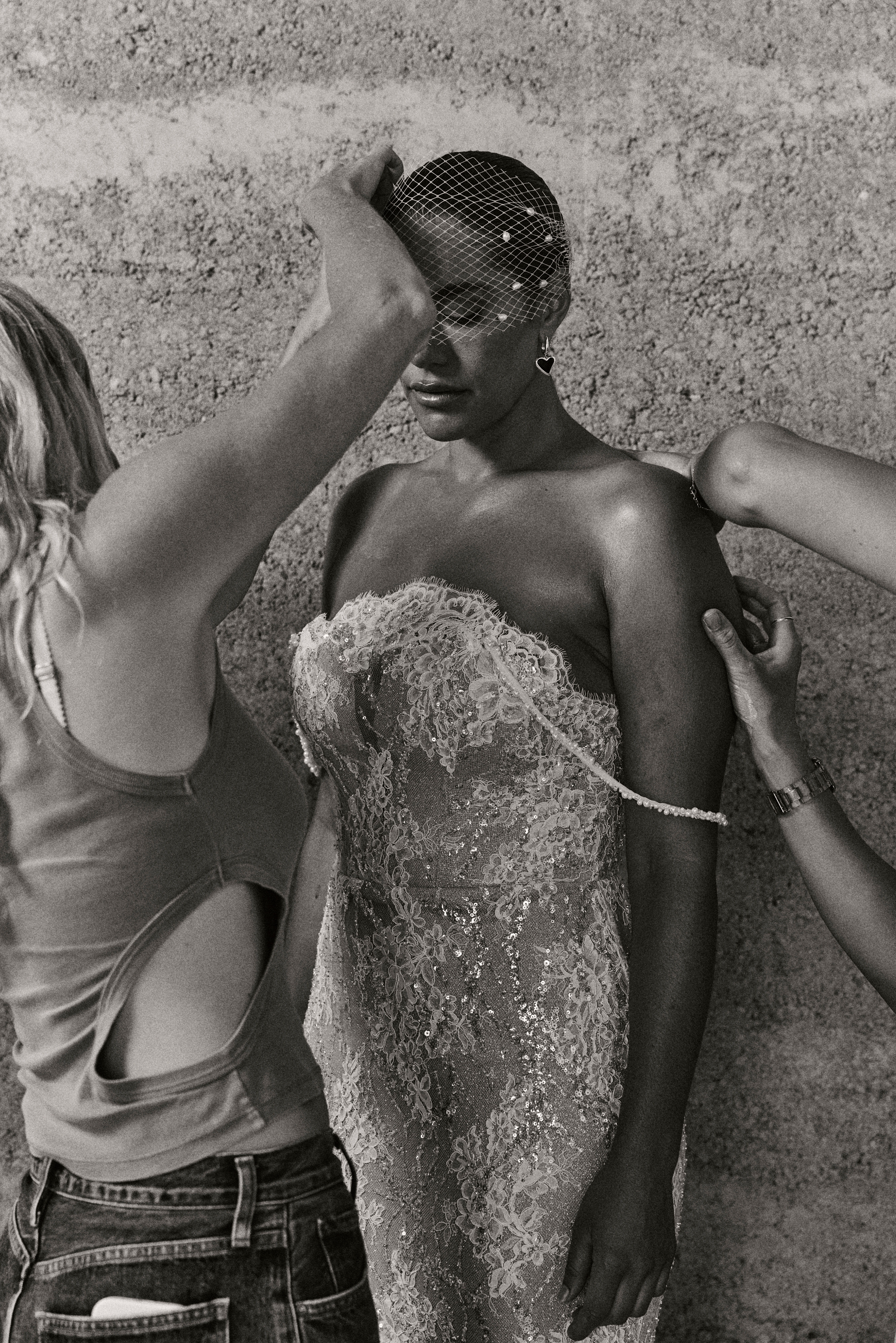 A model is being fitted for a wedding dress by stylists.