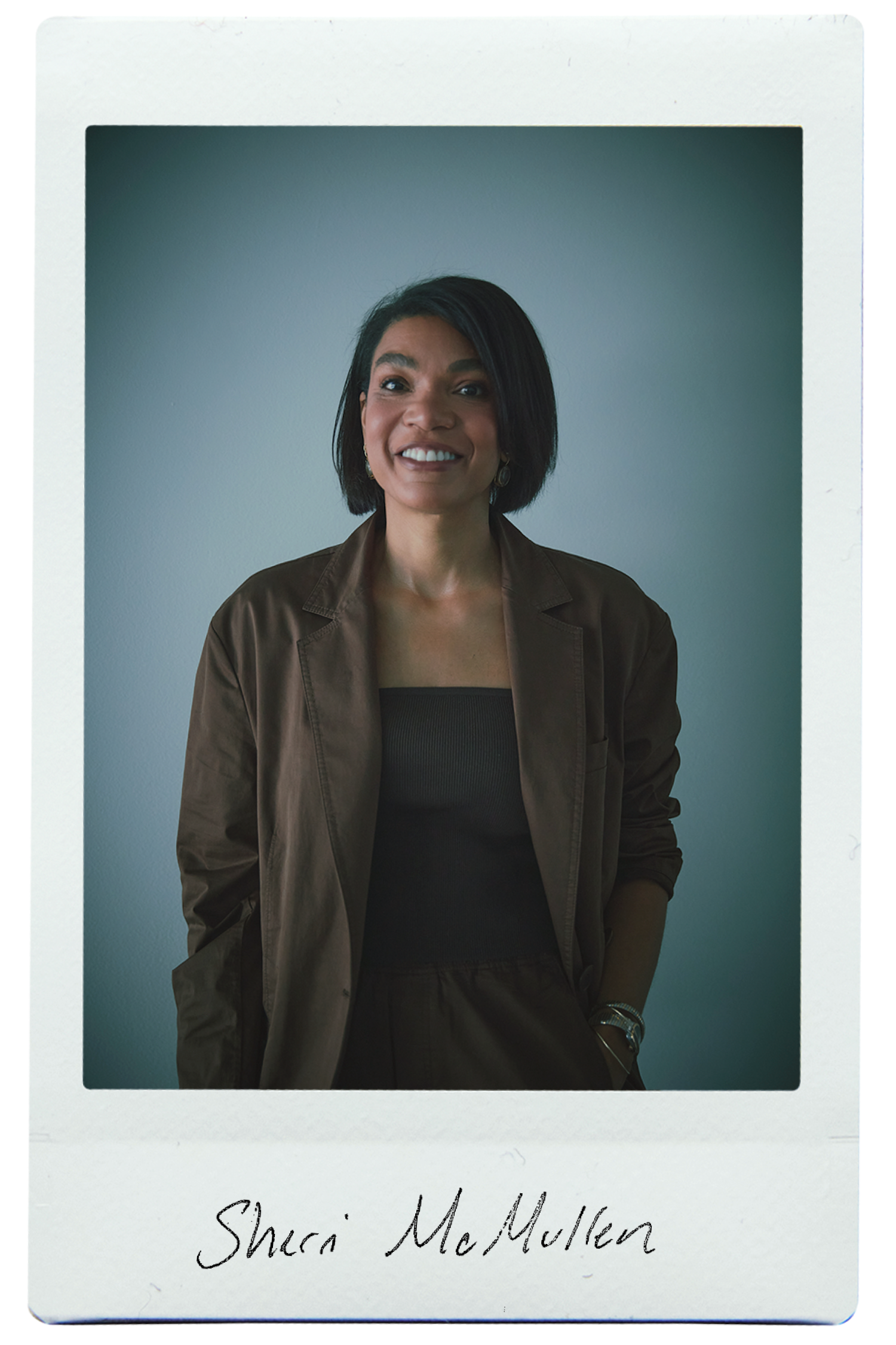 Person smiling in a brown outfit, standing against a muted background.