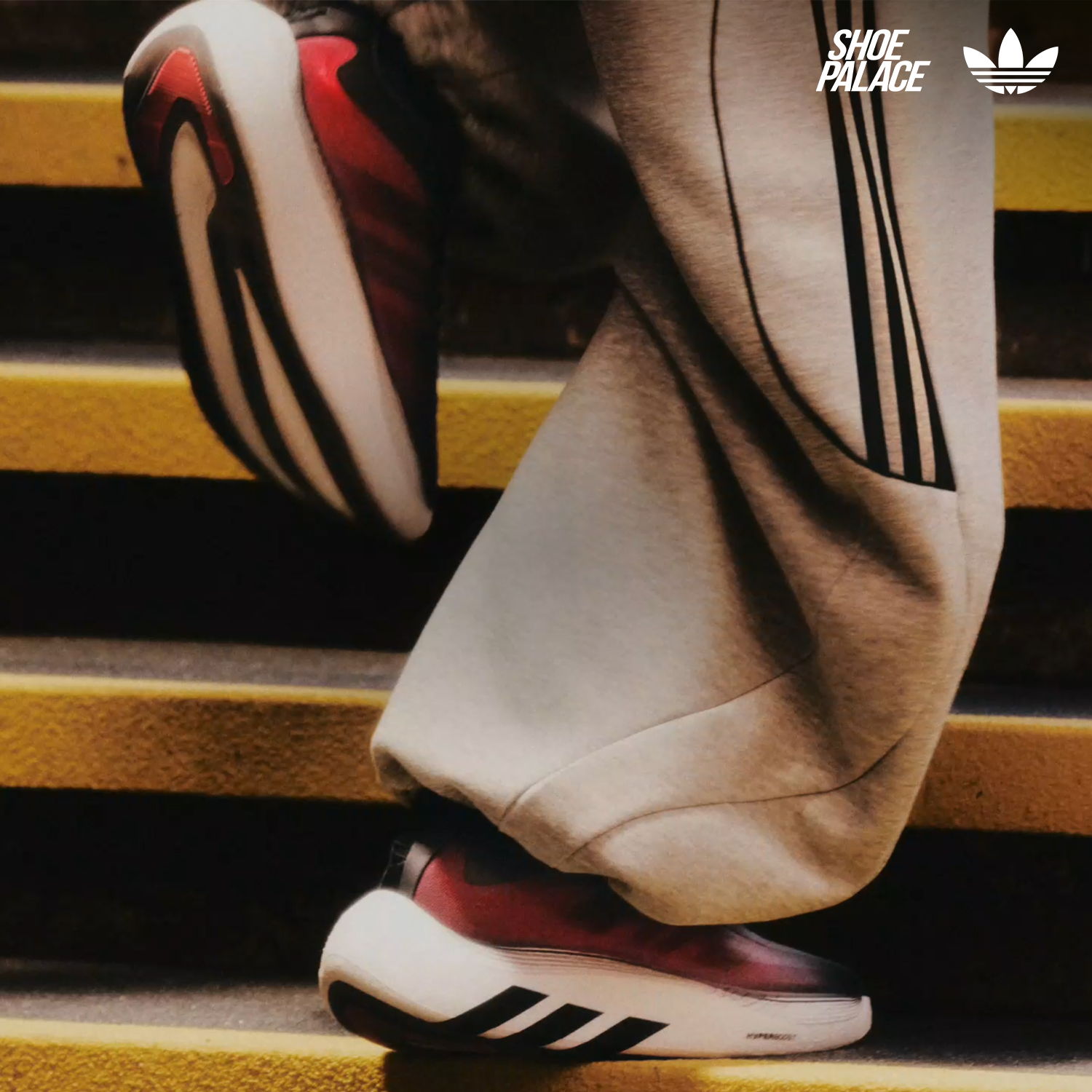 Person wearing Adidas shoes while walking down stairs.