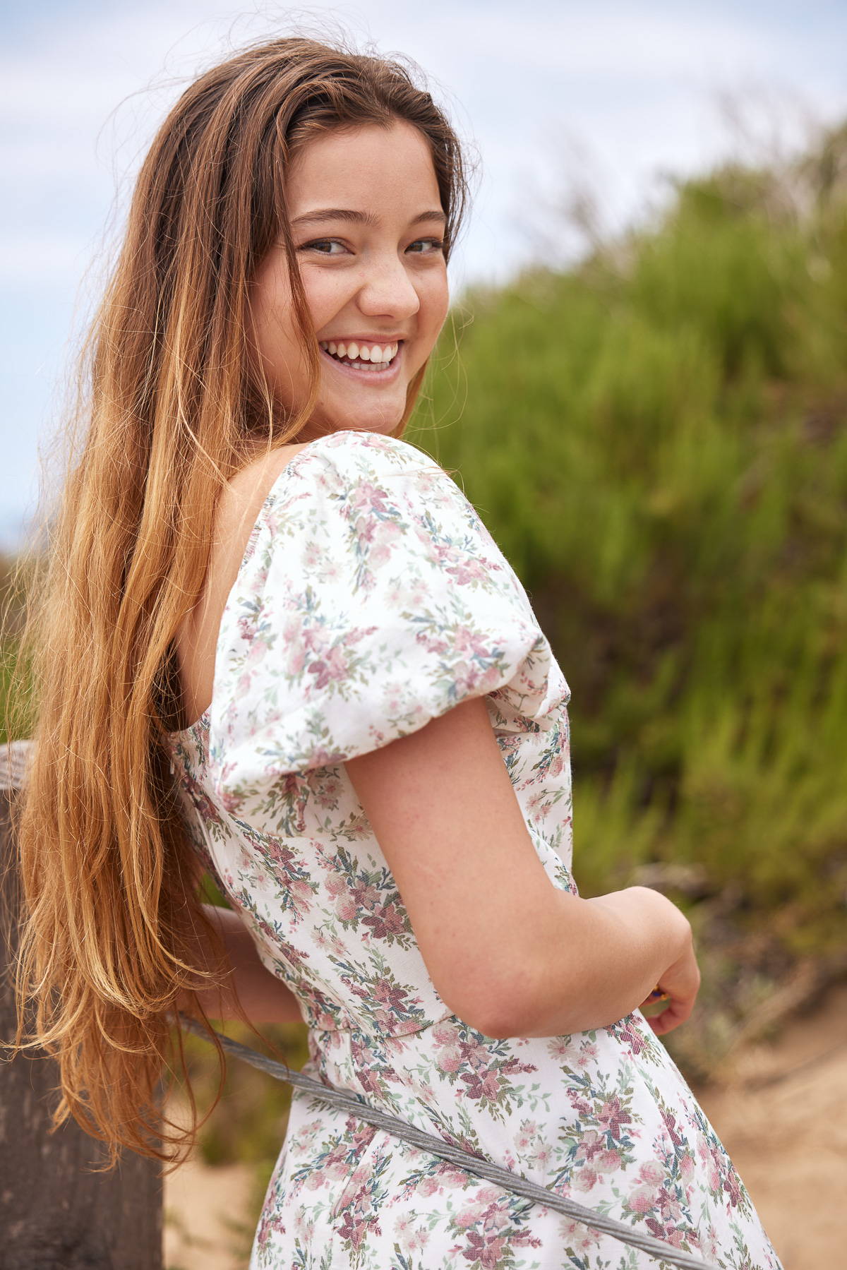 Trixxi sun-kissed summer, girl at ocean side beach pier, in floral wrap ruffle puff sleeve dress.