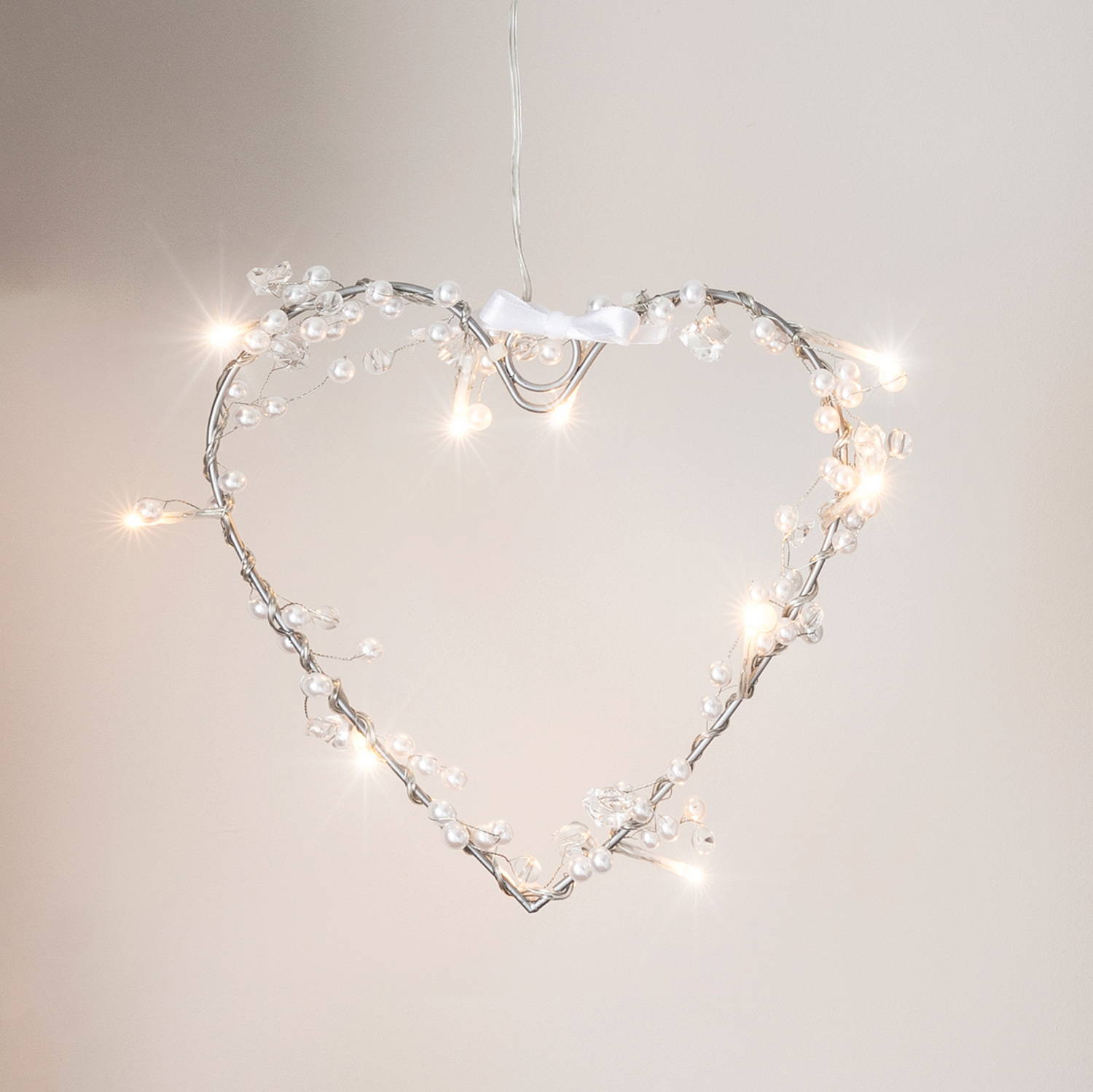 Beaded heart light with a silver metal frame and a warm white light.