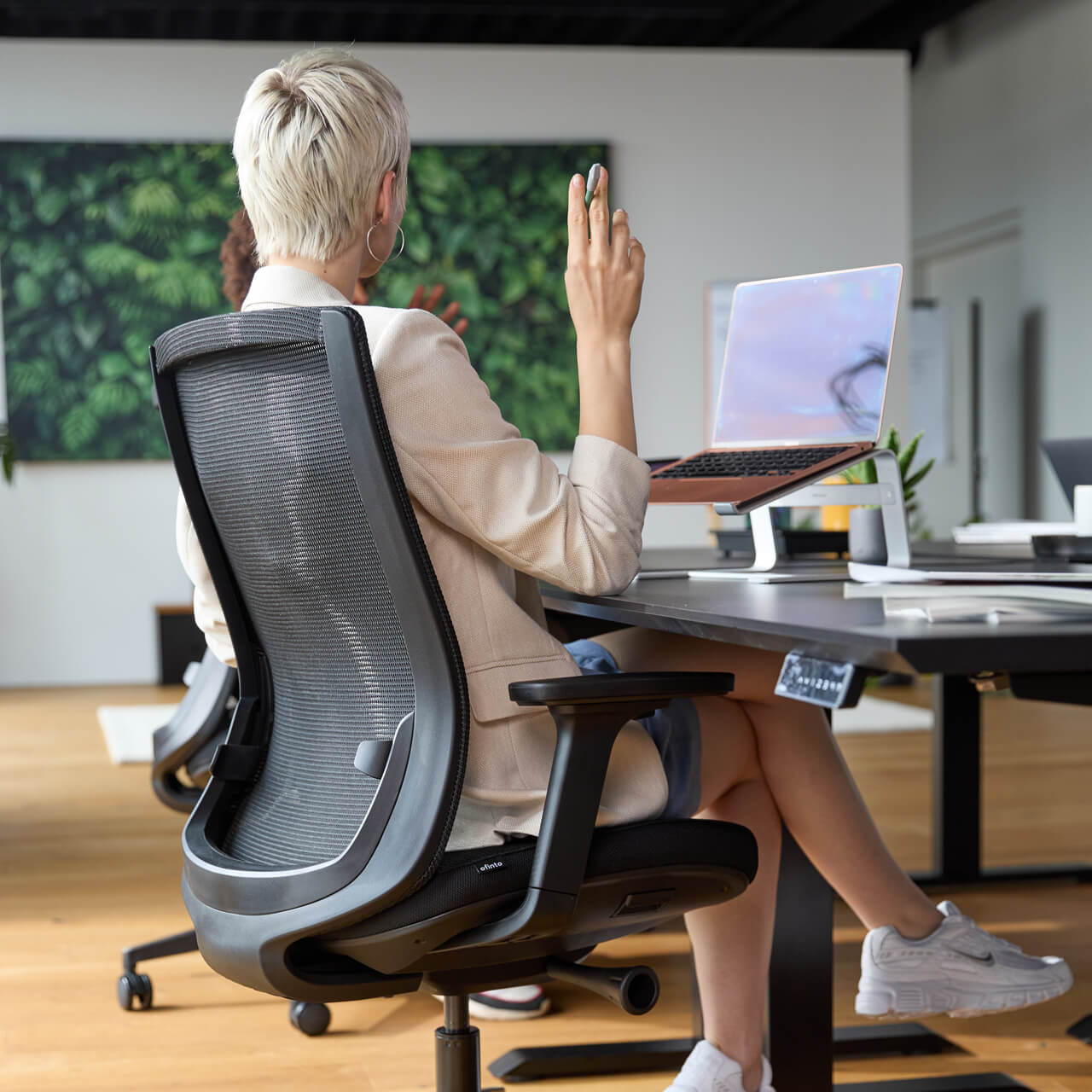 A woman in an open-plan office is sitting on a black ofinto Ergo