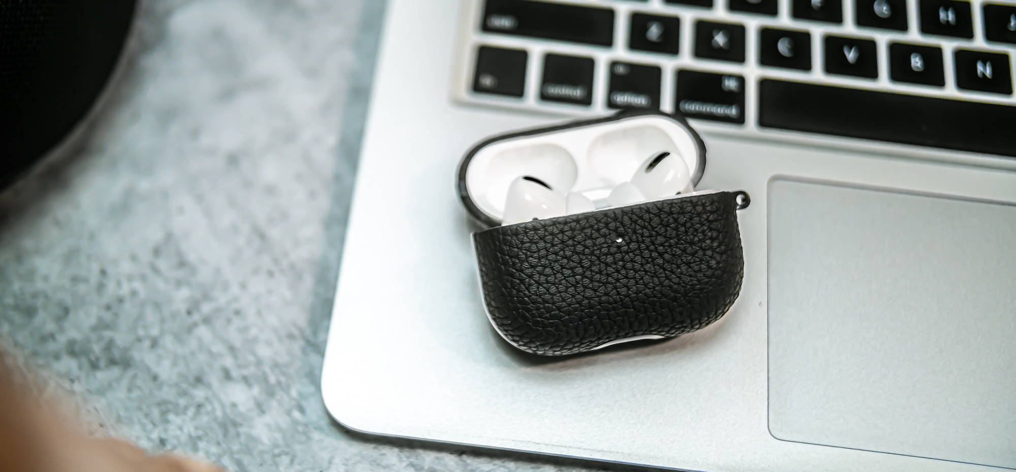 black genuine leather airpods pro case laying on a macbook with the lid open