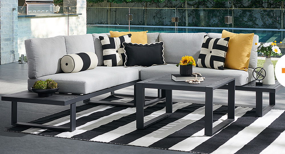 Modern outdoor seating area with cushions and a striped rug.