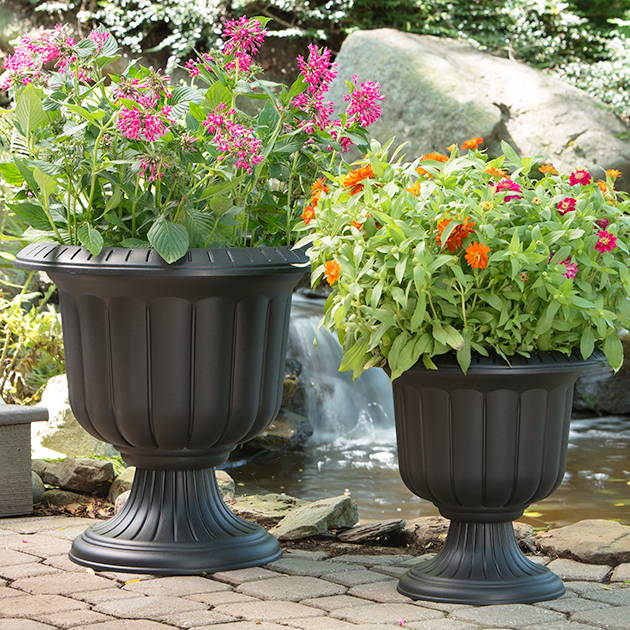 Flowers planted in both small and large, black classic urns