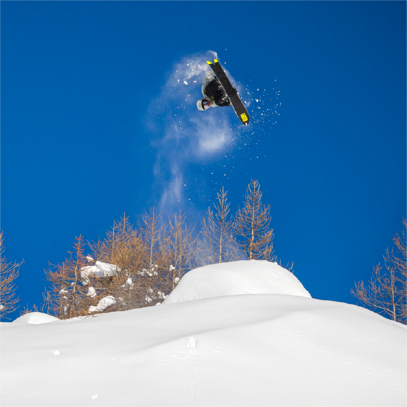 Snowboarder jumping in the air against a clear blue sky.