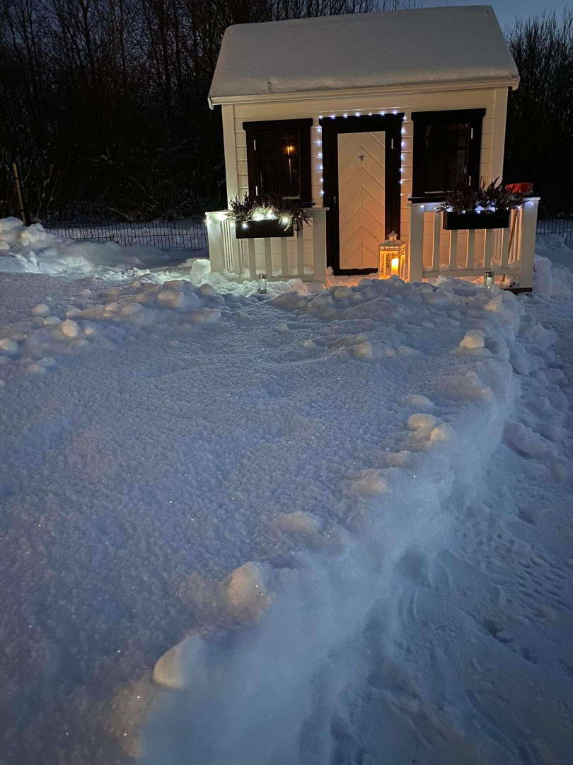 Custom Playhouse decorated with lights in the backyard in winter by WholeWoodPlayhouses