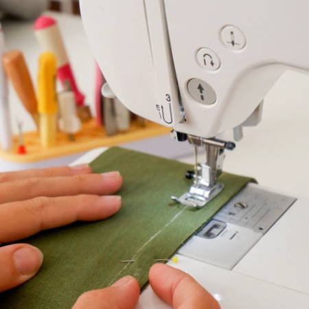 Sewing the seam on the mark on green fabric with a regular sewing machine