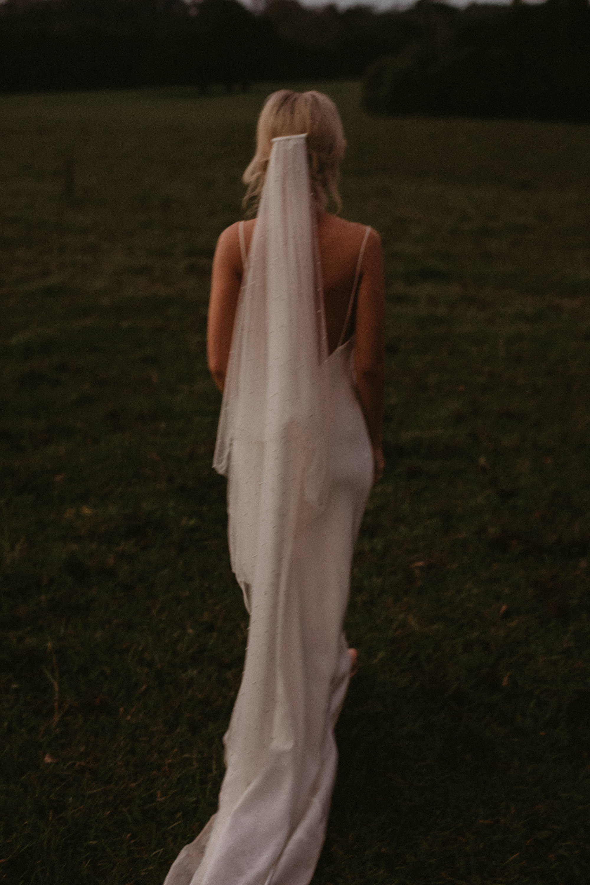 Bride wearing a peal long tulle veil in a grass field