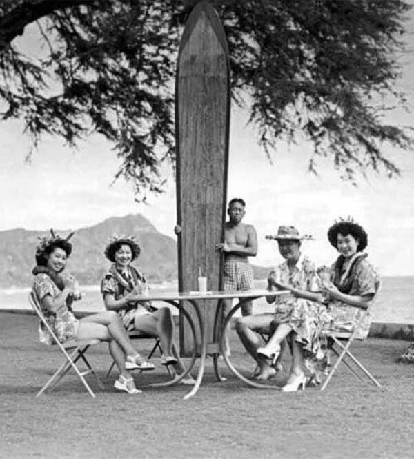 A vintage mood image of a Japanese family sat around a table with a surf board.