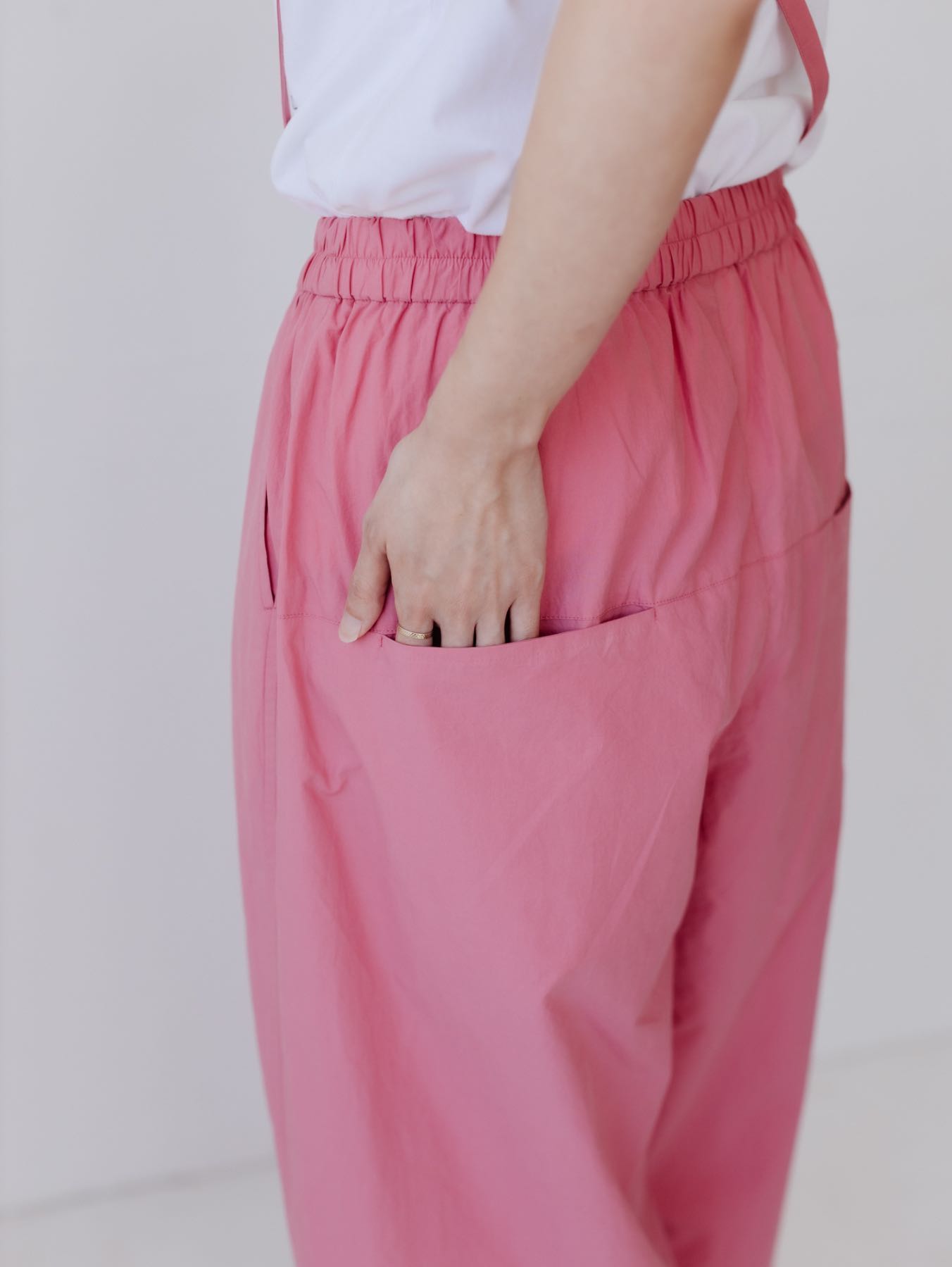 A person wearing pink pants with a hand in the pocket.