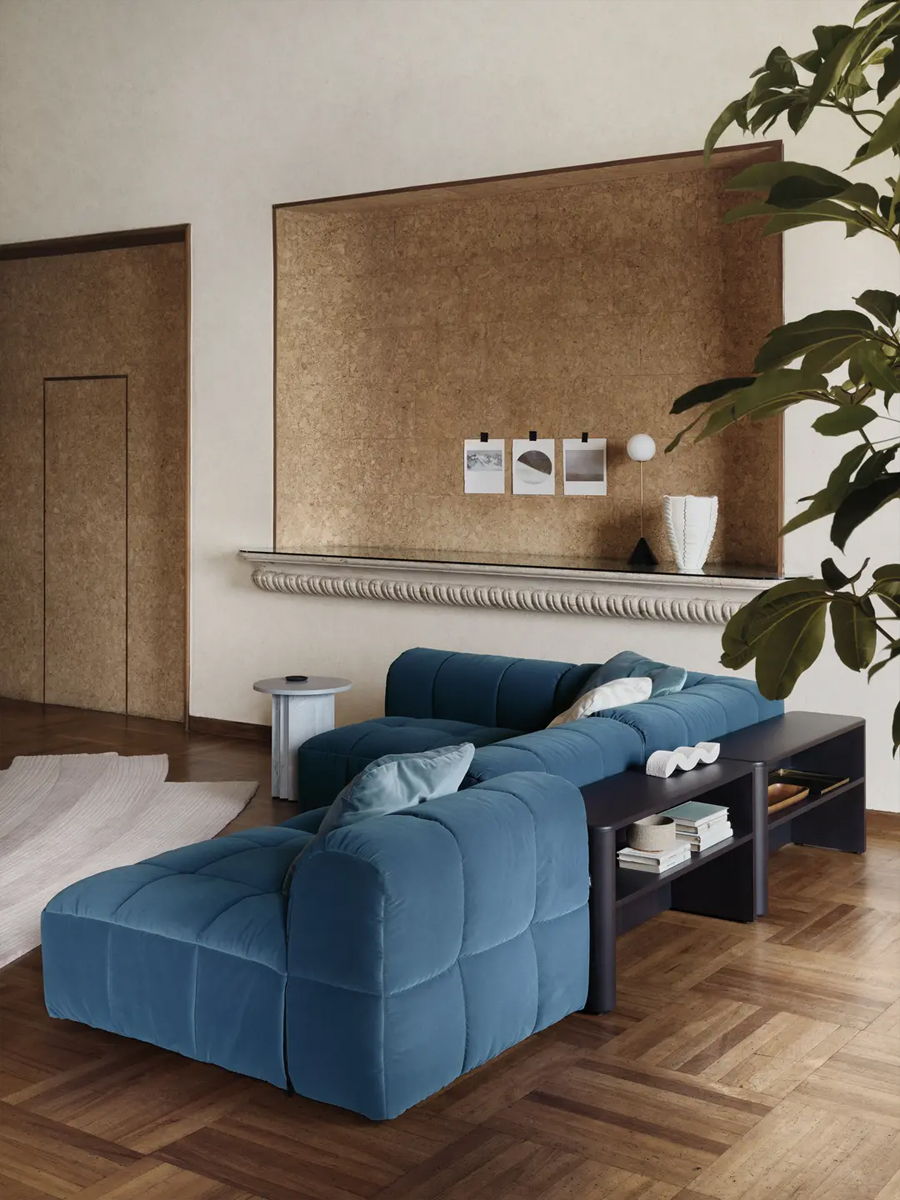 Modern living room with a blue sofa, wooden flooring, and decorative wall.