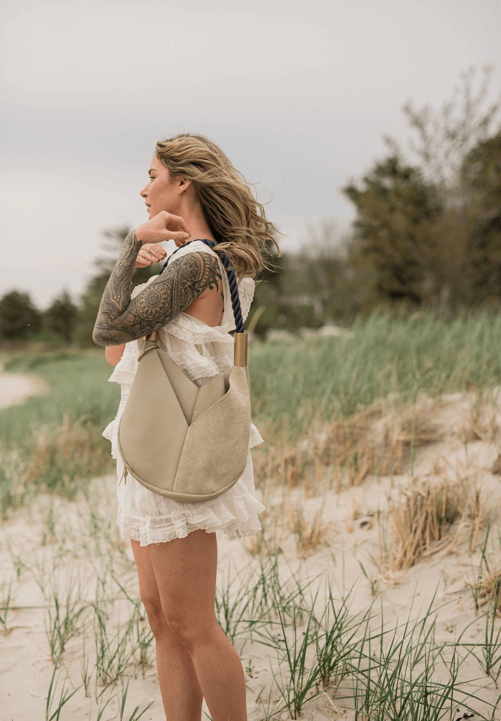 woman wearing a beige leather tote in the dunes
