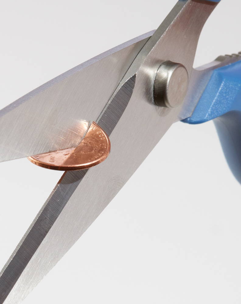 A set of Blue Misen Kitchen Shears cutting cleanly through a penny coin.