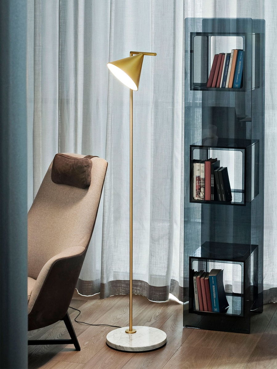 A modern reading corner with a floor lamp and bookshelf.