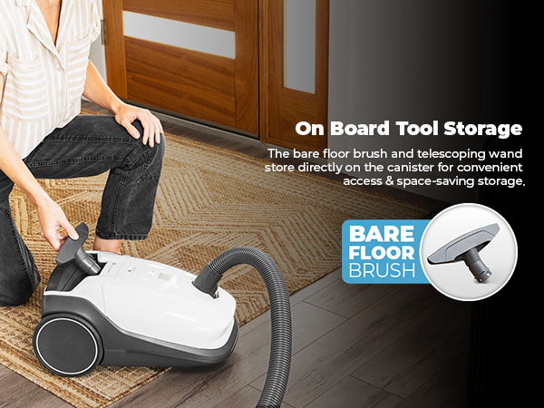 Person using a vacuum cleaner with tool storage features on a floor.