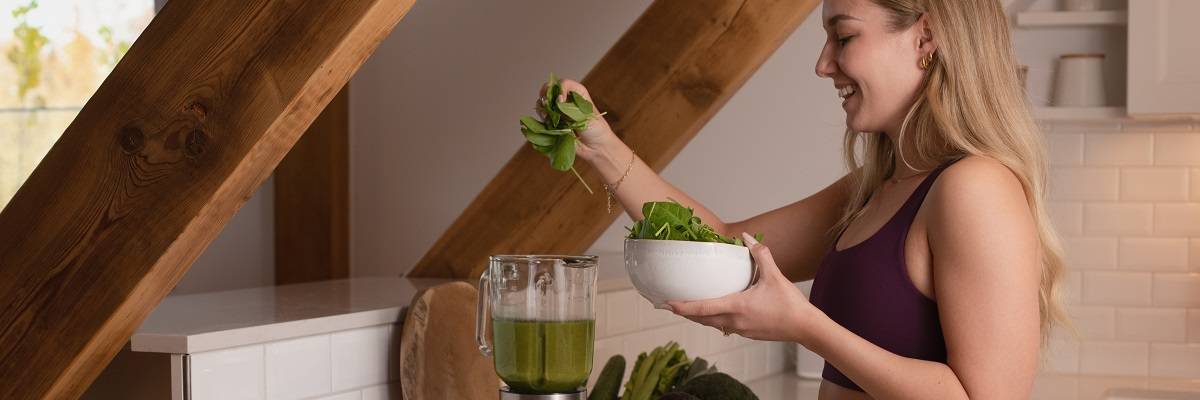 Una donna mette gli spinaci nel frullato verde