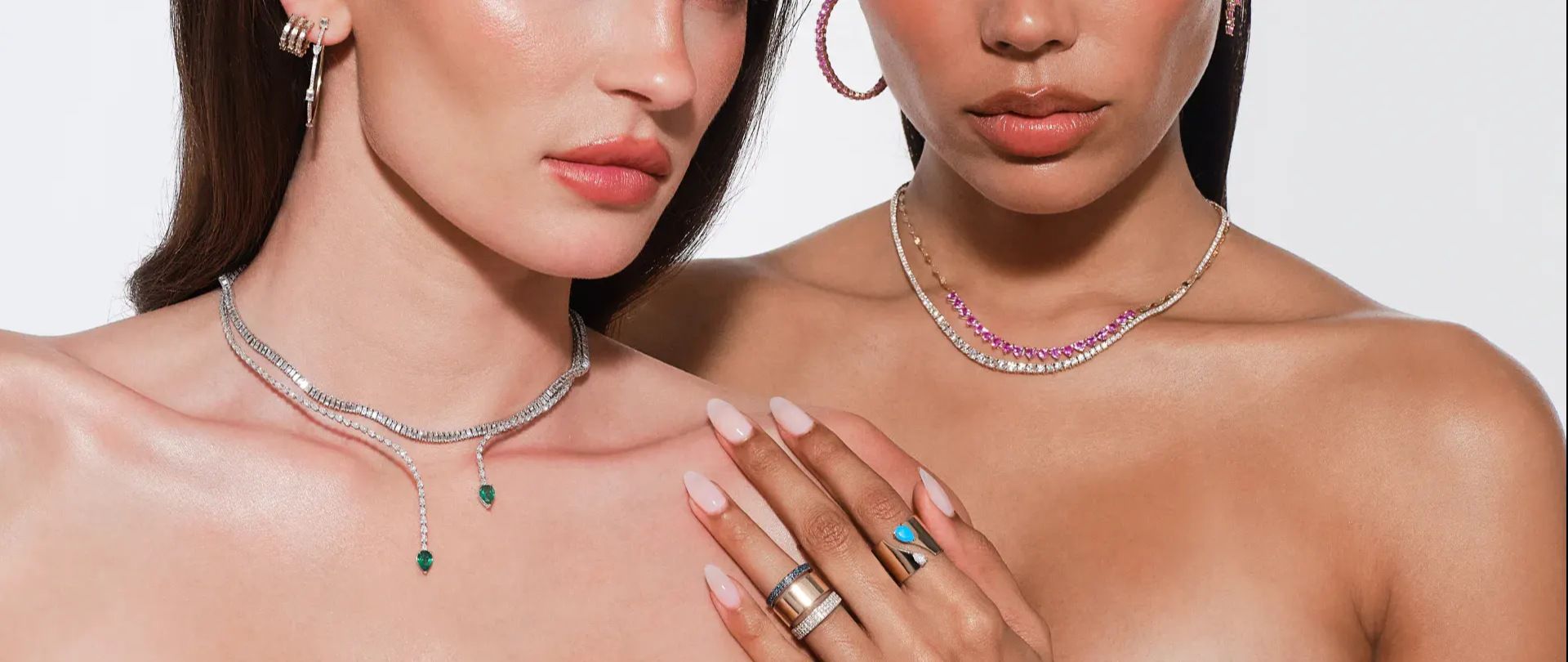 Two models wearing pink sapphire and emerald jewelry.