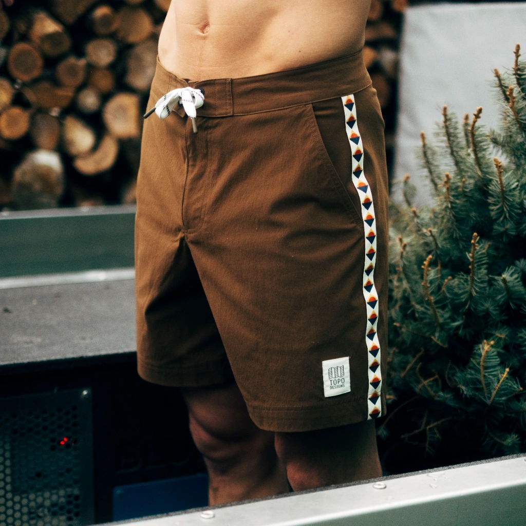 A person wearing brown shorts with a decorative side pattern.