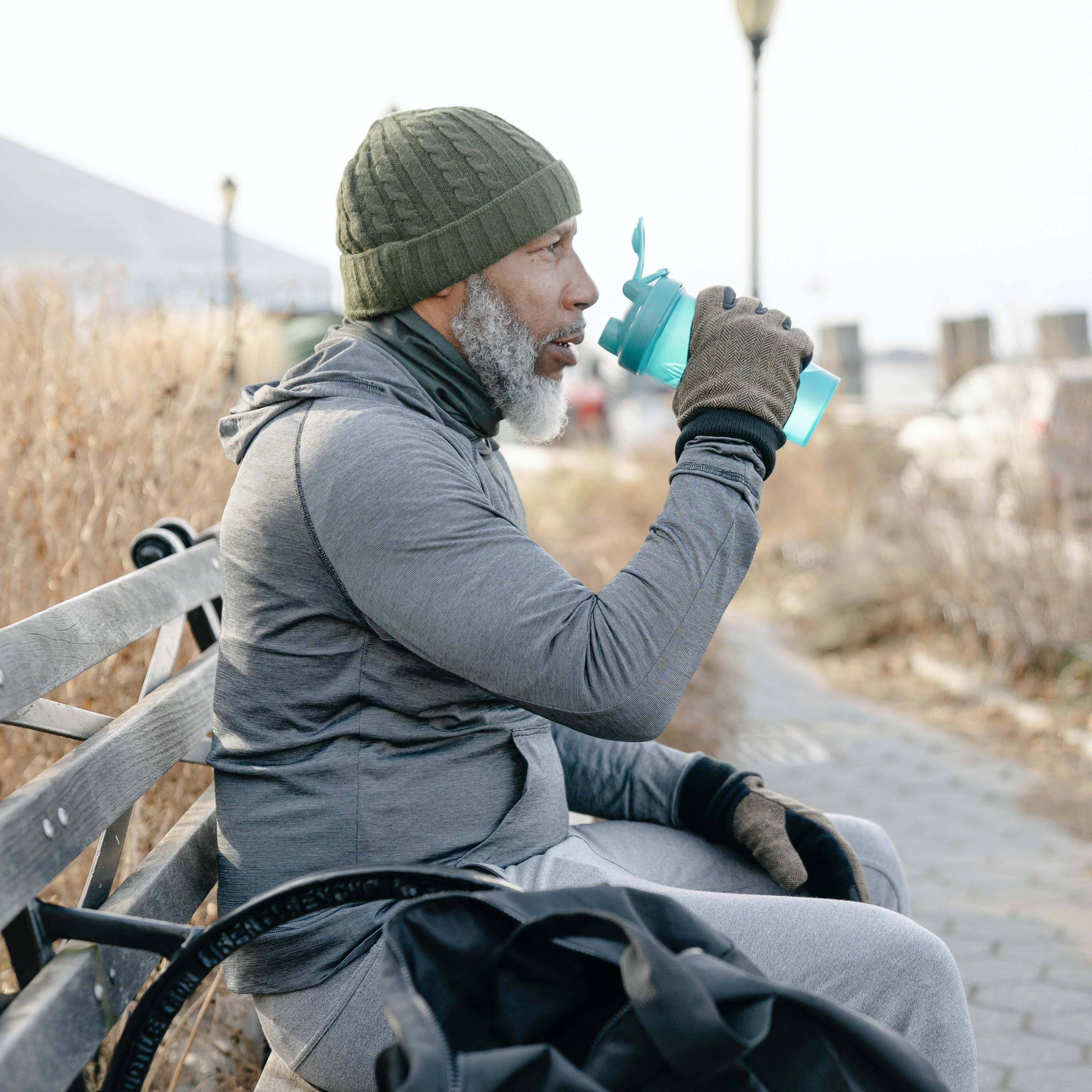 Man sitting on a bench drinking water