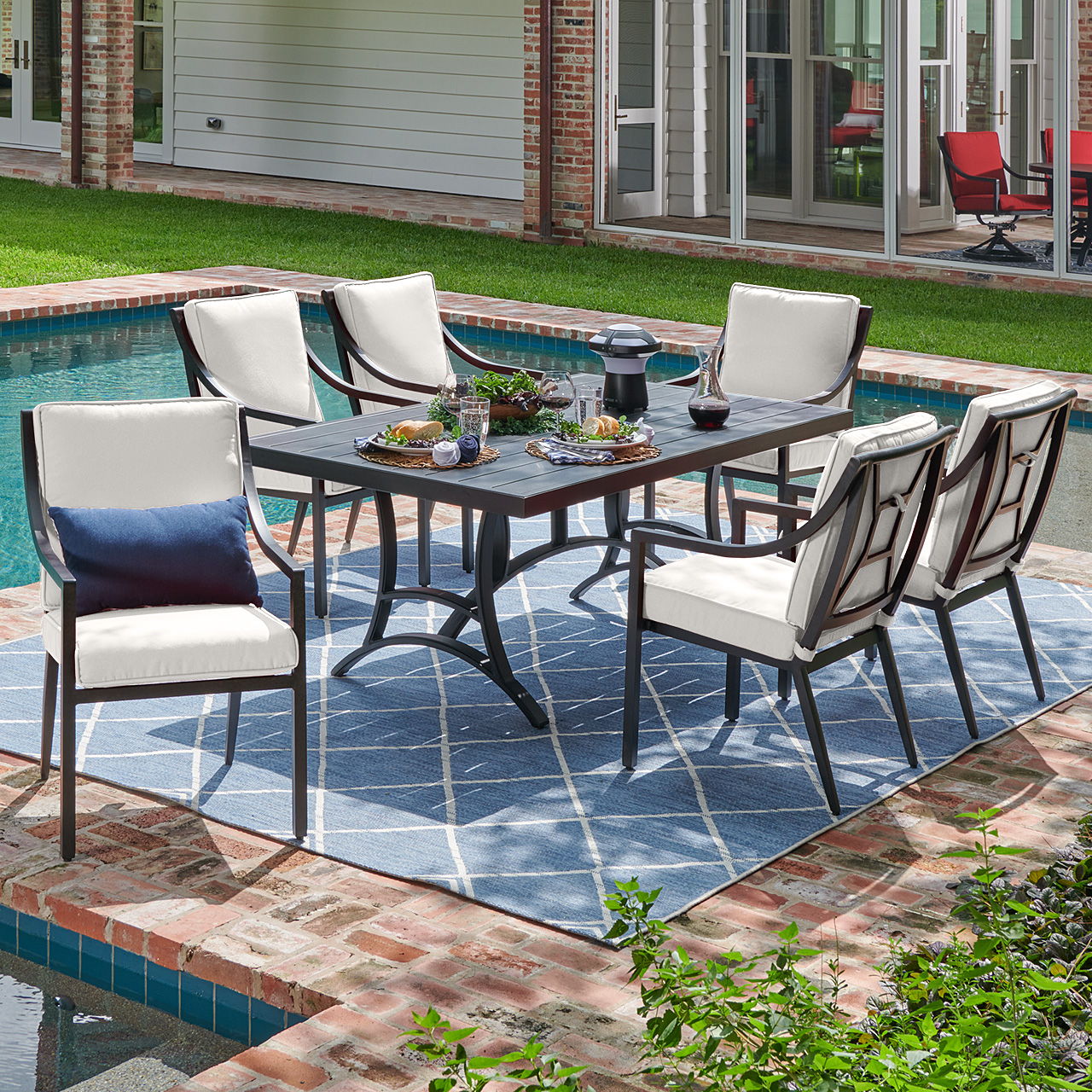 Outdoor dining set by a poolside with chairs and table.