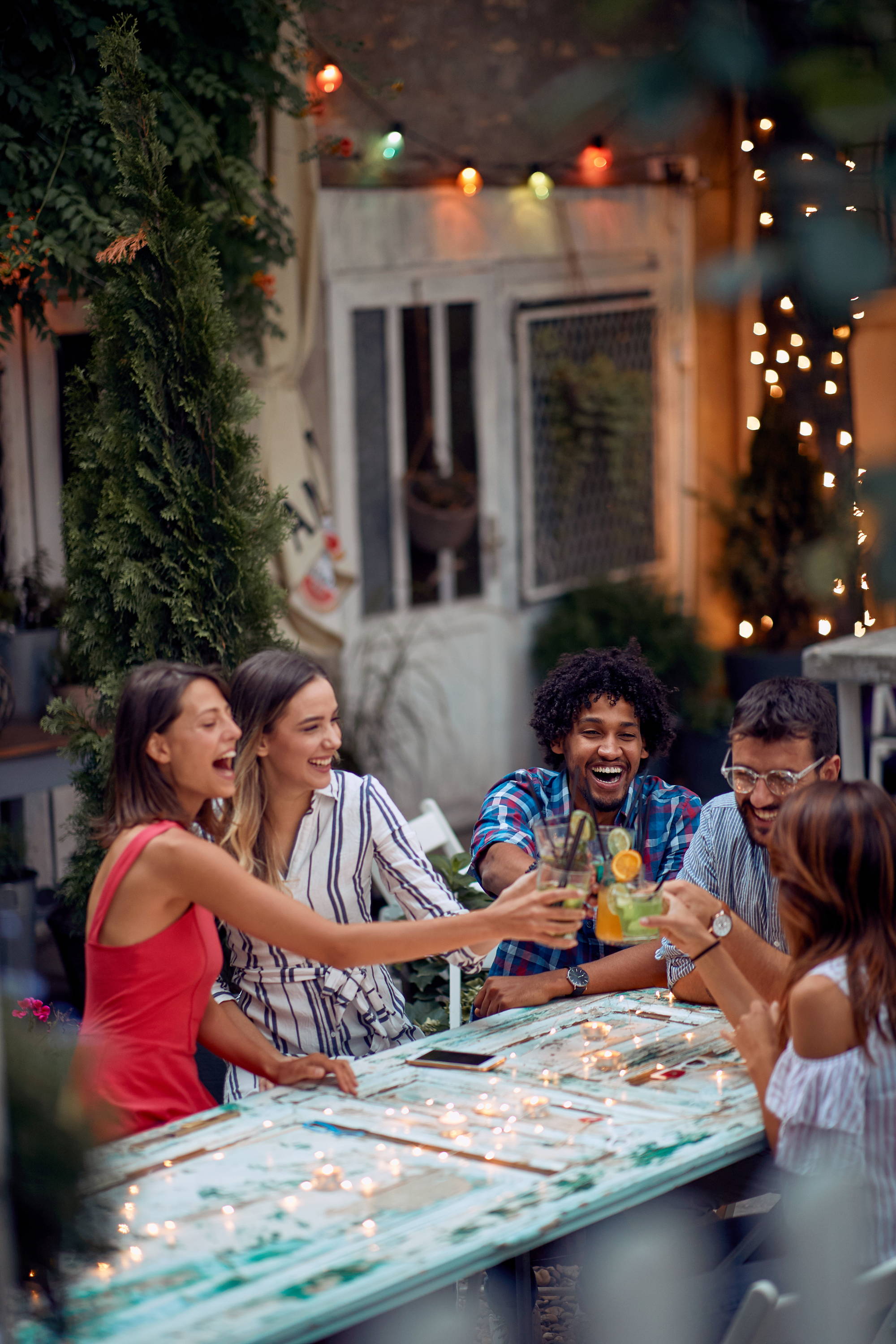 Group of young adults laughing and having drinks