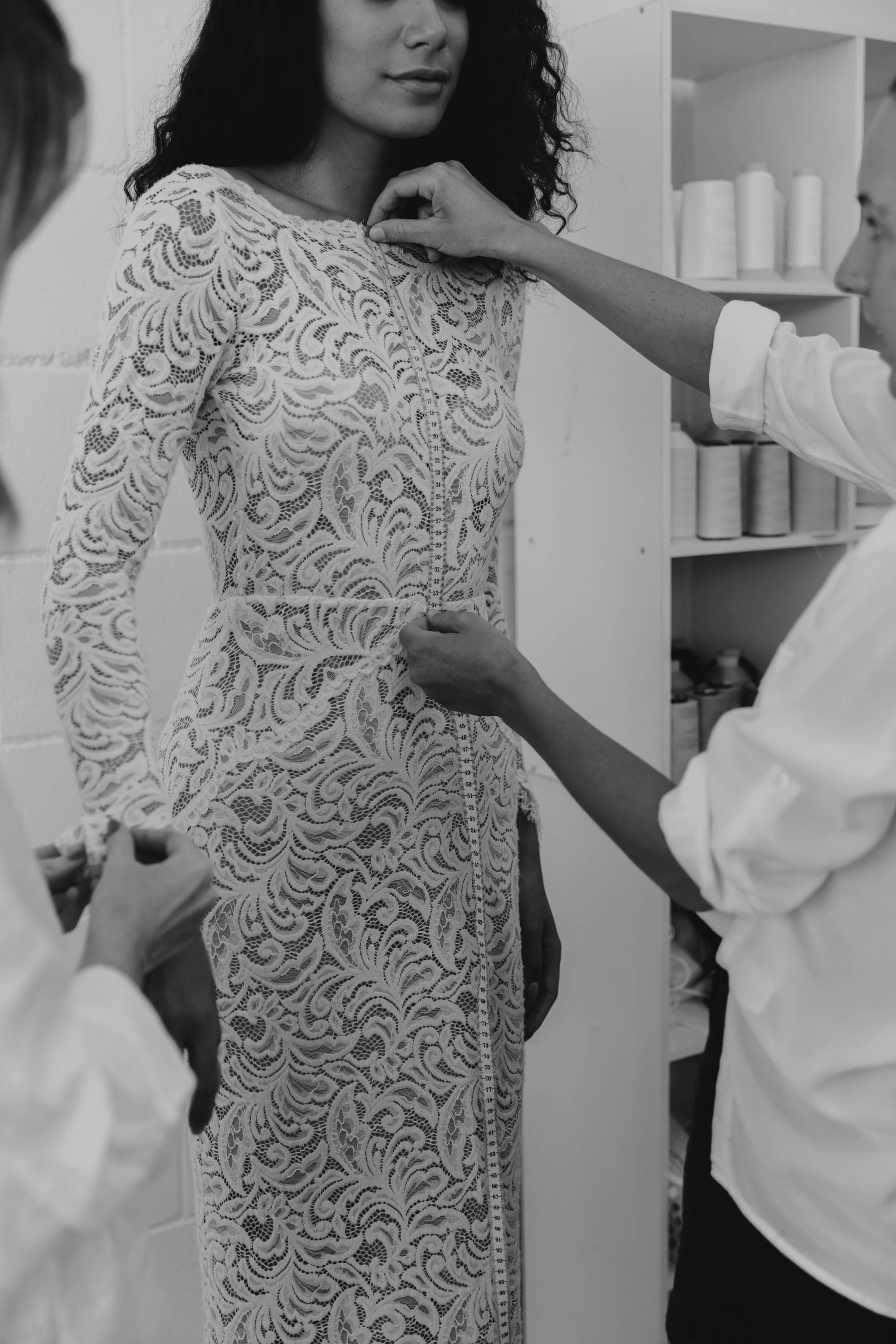 Seamstress measuring up a long sleeve lace dress