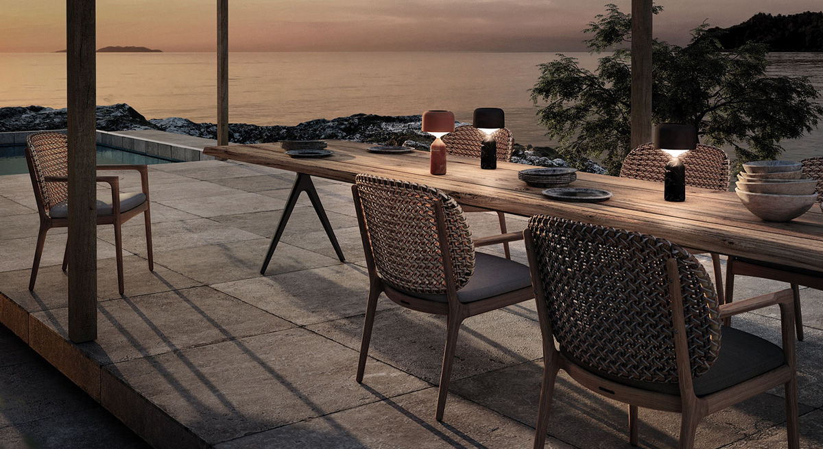 Dining area with Gloster Pebble lanterns overlooking a tranquil sunset by the water.