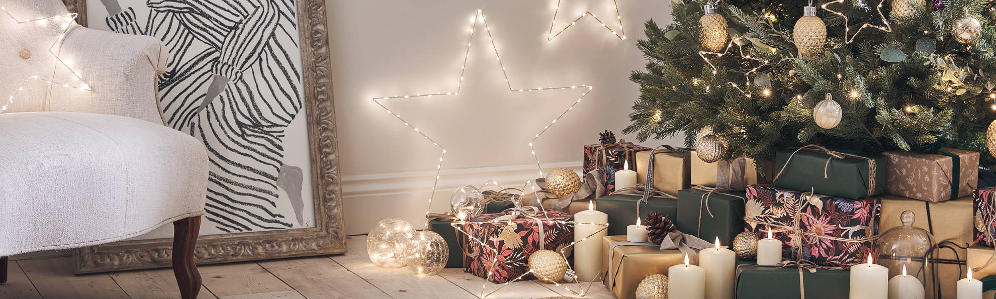 Sapin de nöel décoré par des boules dorées, avec des cadeaux et des étoiles lumineuse dans le salon. 