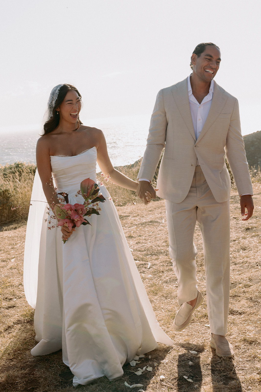 Bride and groom walking together on a sunny outdoor path.