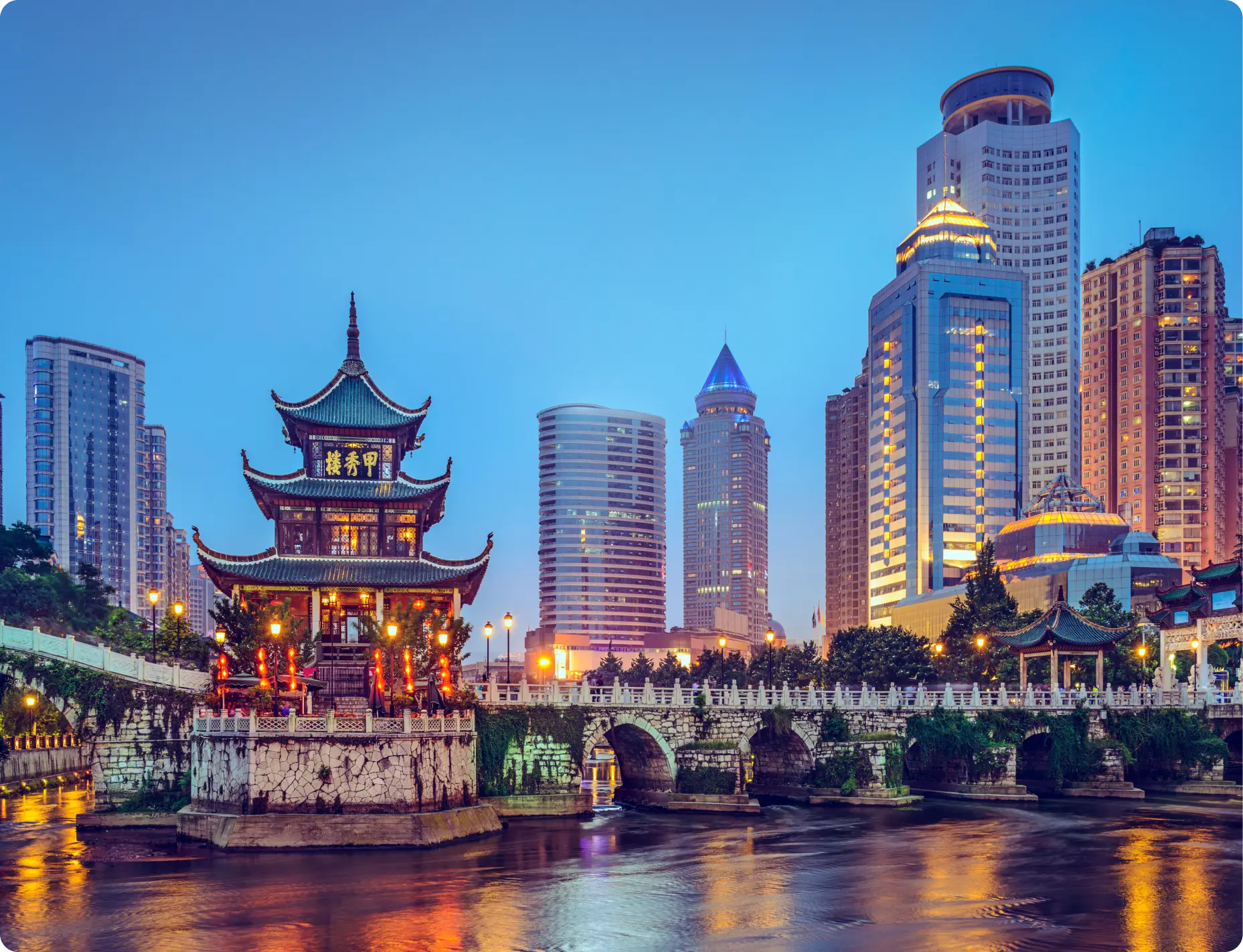 Night view of a traditional pavilion by modern skyscrapers.