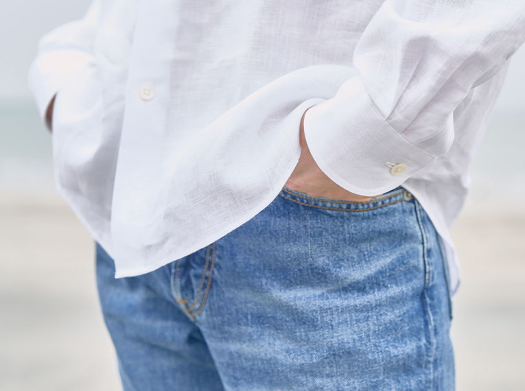 Person wearing a white shirt and jeans with hands in pockets.