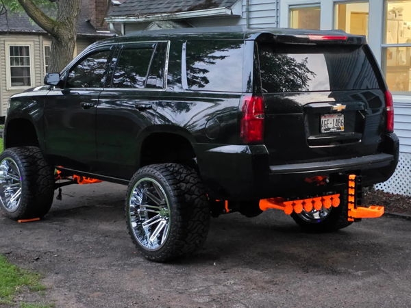 Rear three-quarter view of Theo's black Tahoe showing the bright orange rear-mounted train horn setup, install photo 2