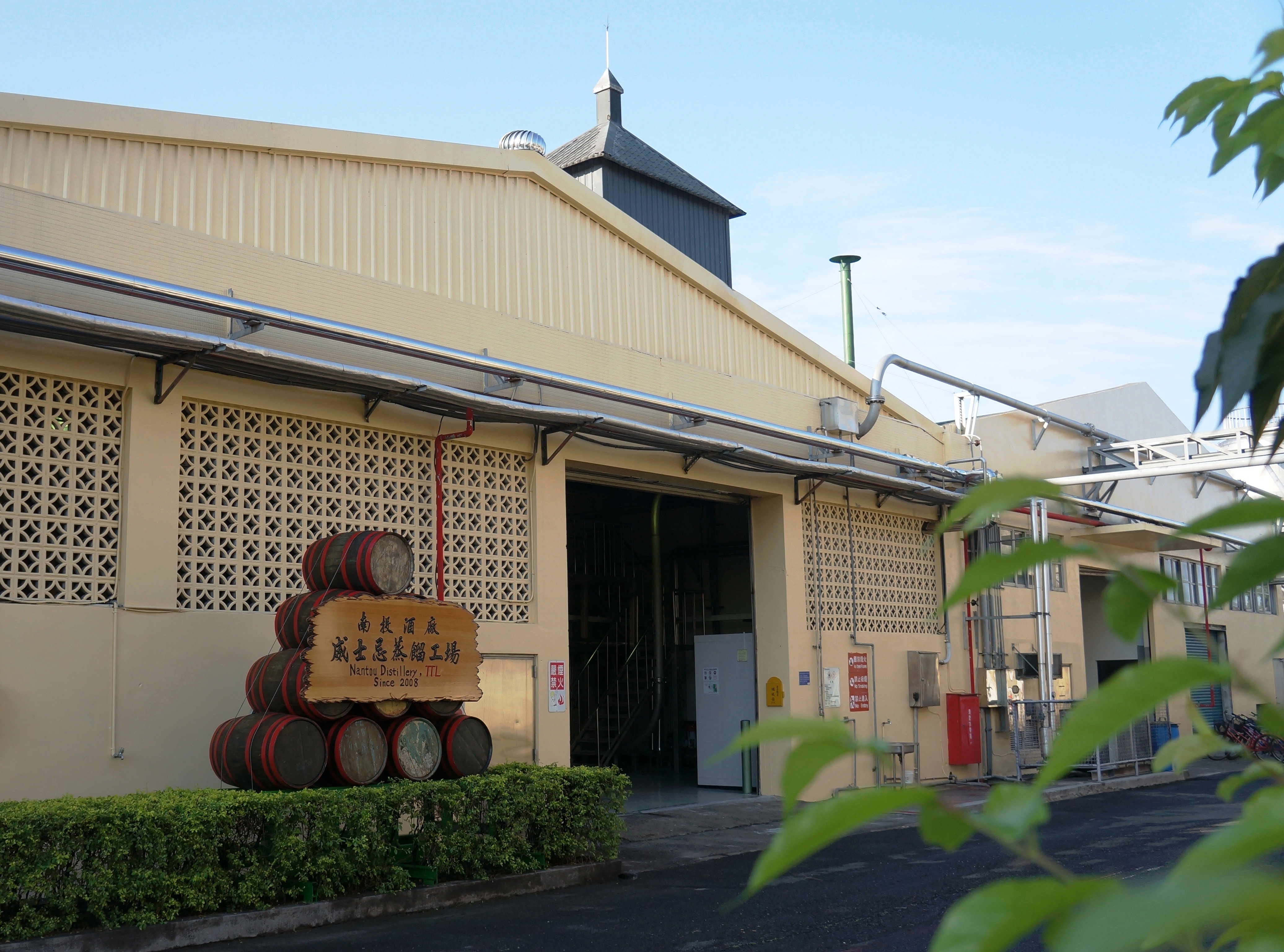 Warehouse exterior with stacked barrels and clear blue sky.