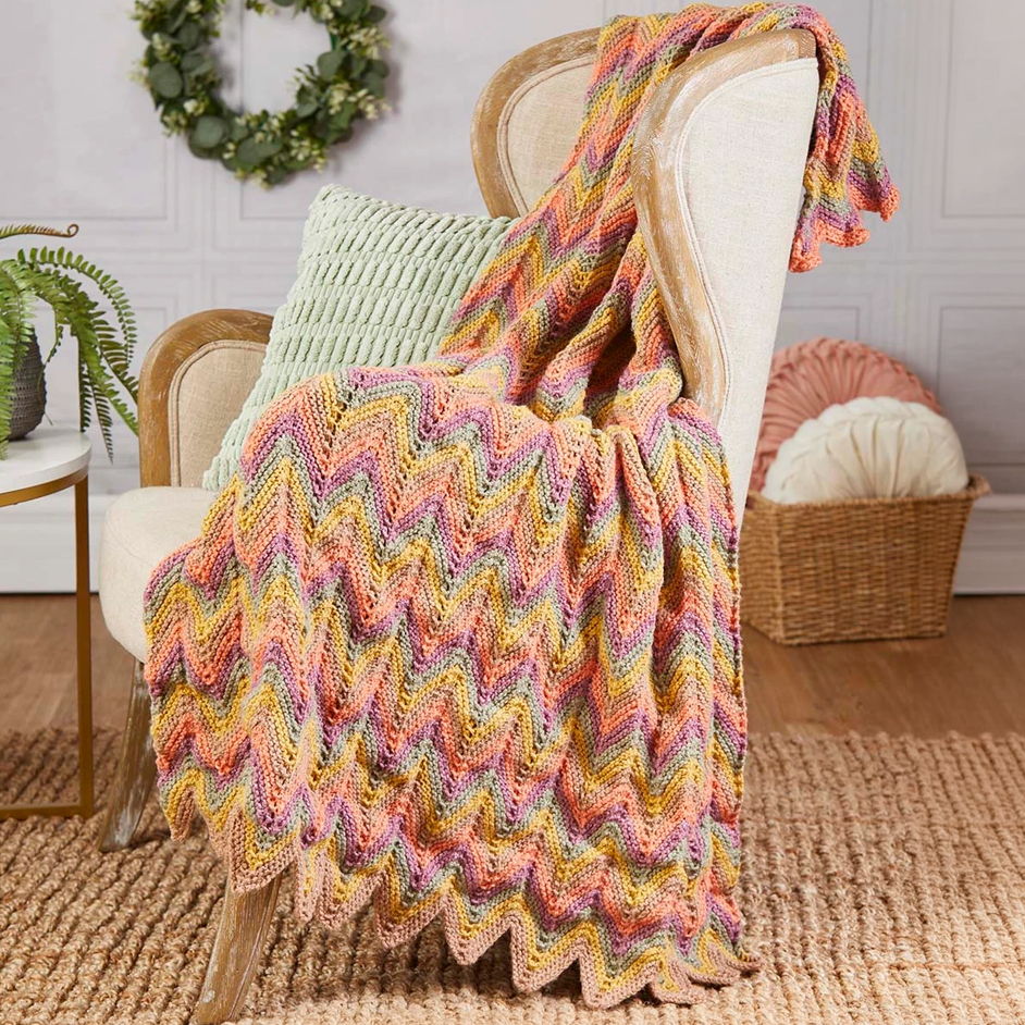 A colorful knitted blanket draped over a chair in a cozy setting.