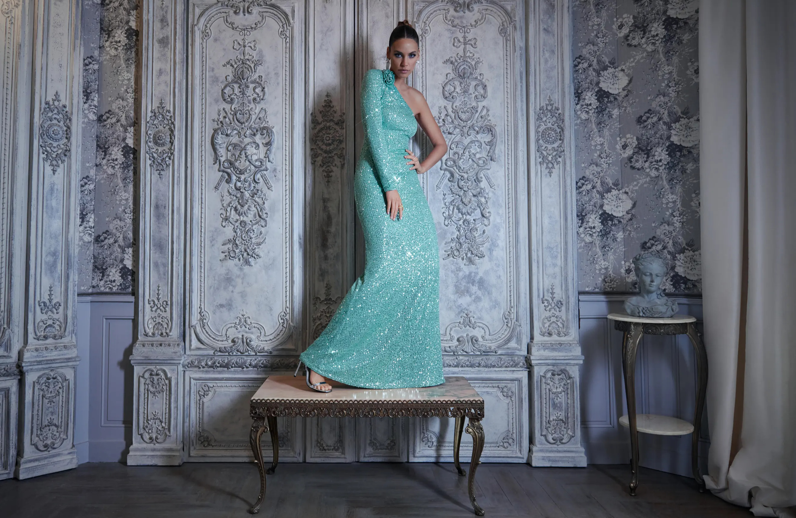 A gorgeous woman posing on a table in a mint sequin maxi dress