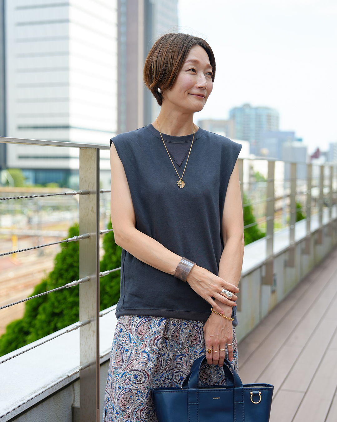 Woman wearing a sleeveless top and patterned pants, standing outdoors.