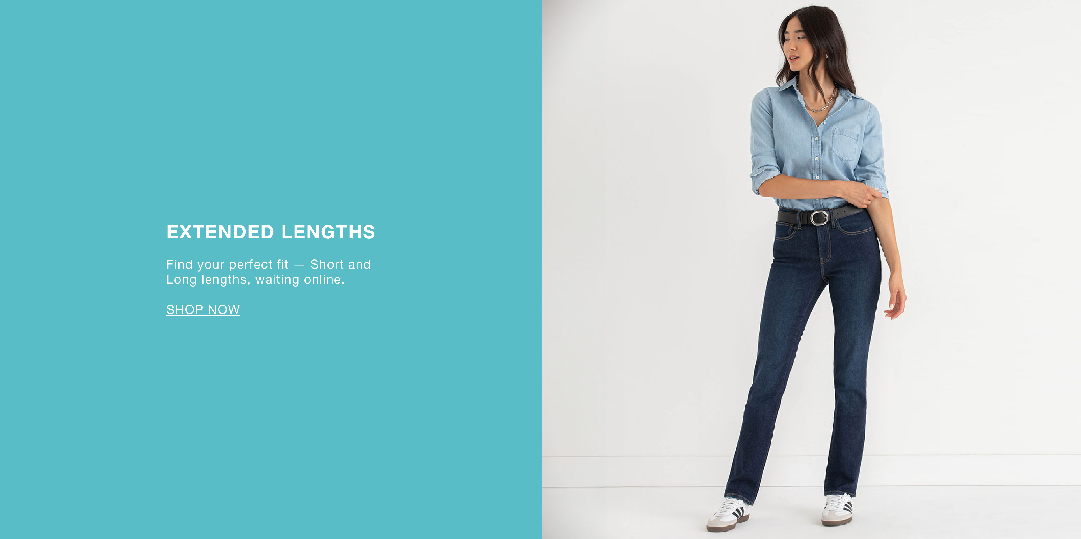 Woman in a blue shirt and dark jeans standing against a light background.