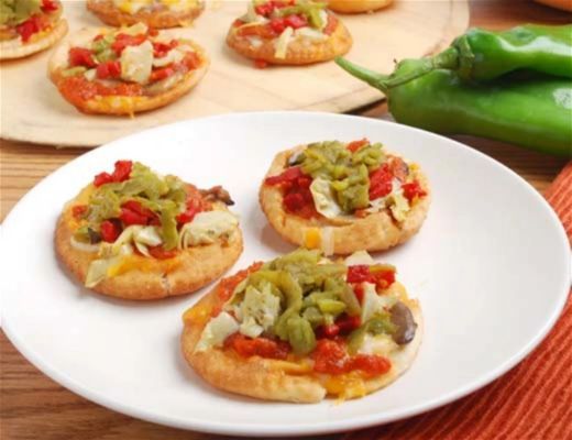 Mini pizzas topped with peppers and vegetables on a white plate.