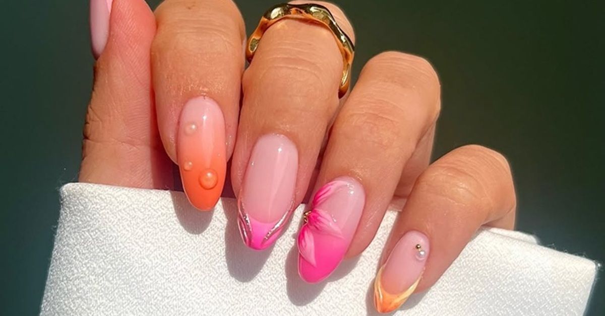 A hand with colorful nail art and a ring on the finger.