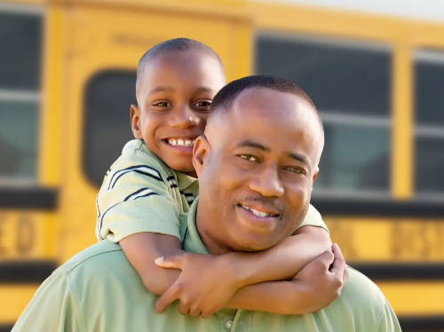 Dad and son hugging by school bus