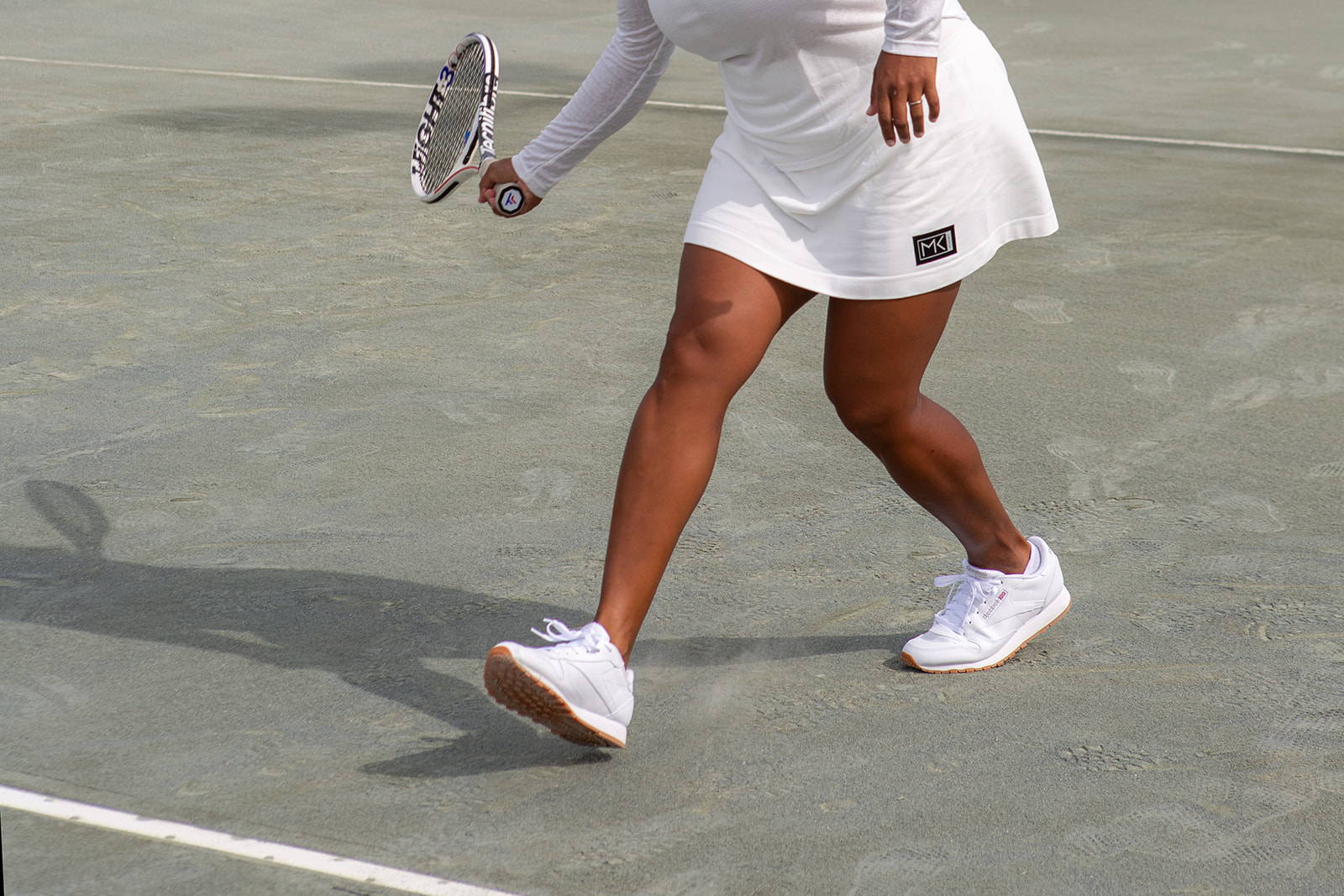 woman playing tennis in a white tennis skirt