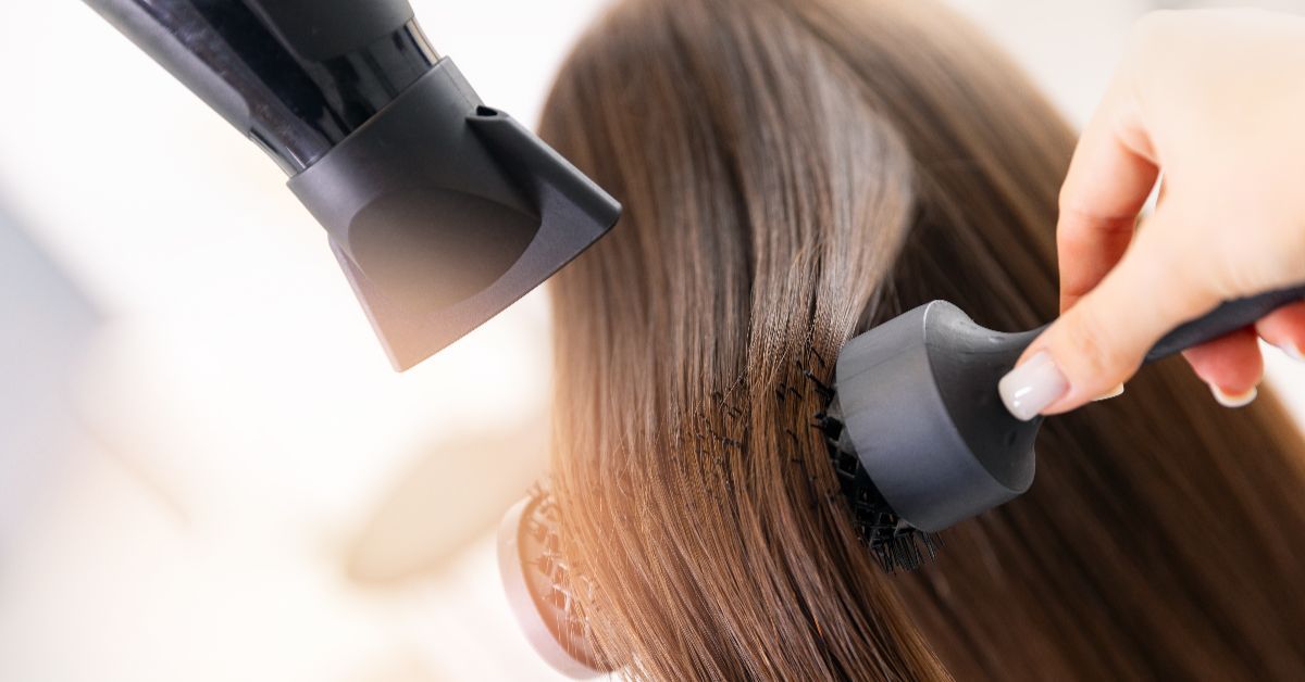 A person using a hairdryer and brush on long hair.