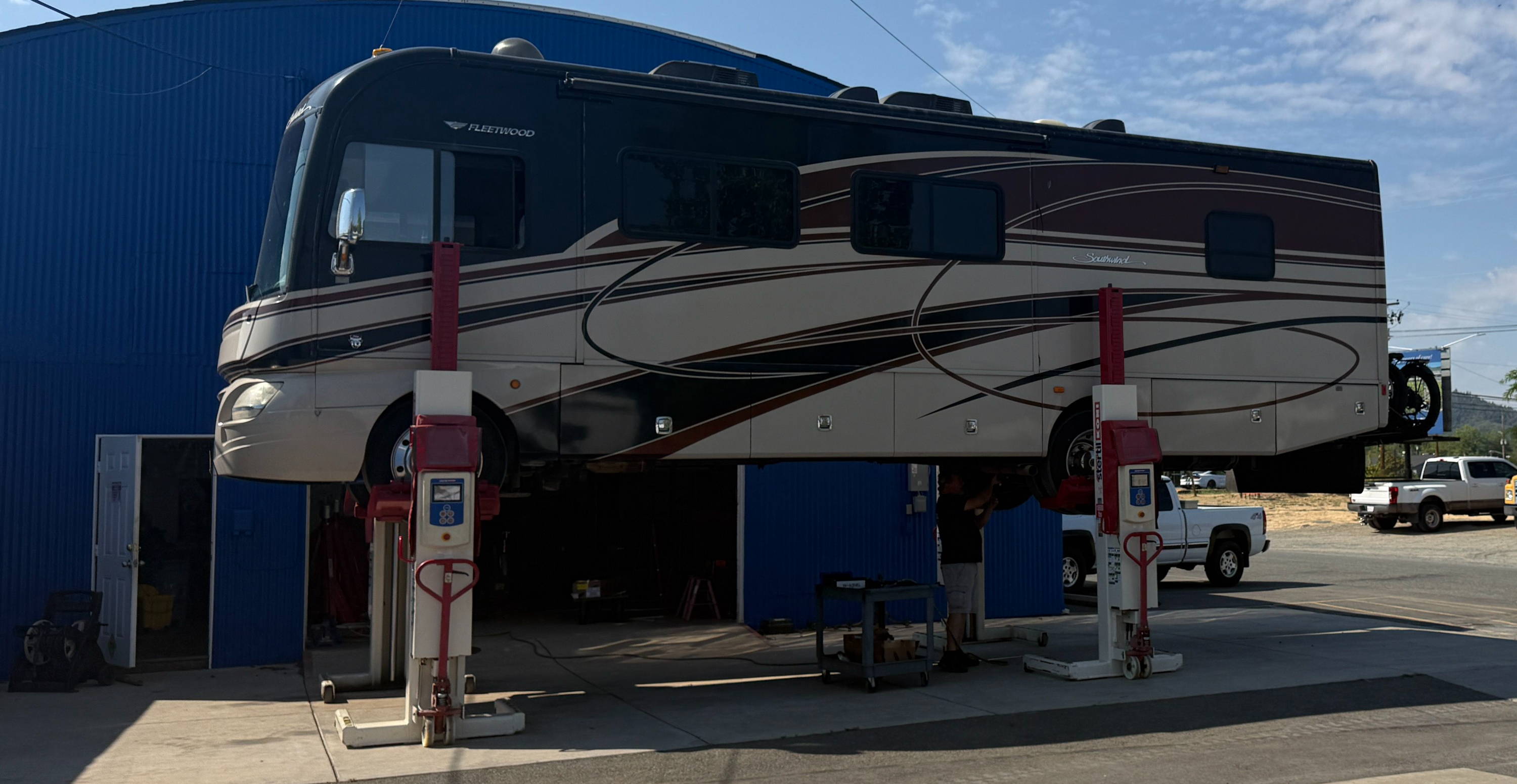 A large RV parked at a service station under a blue sky.