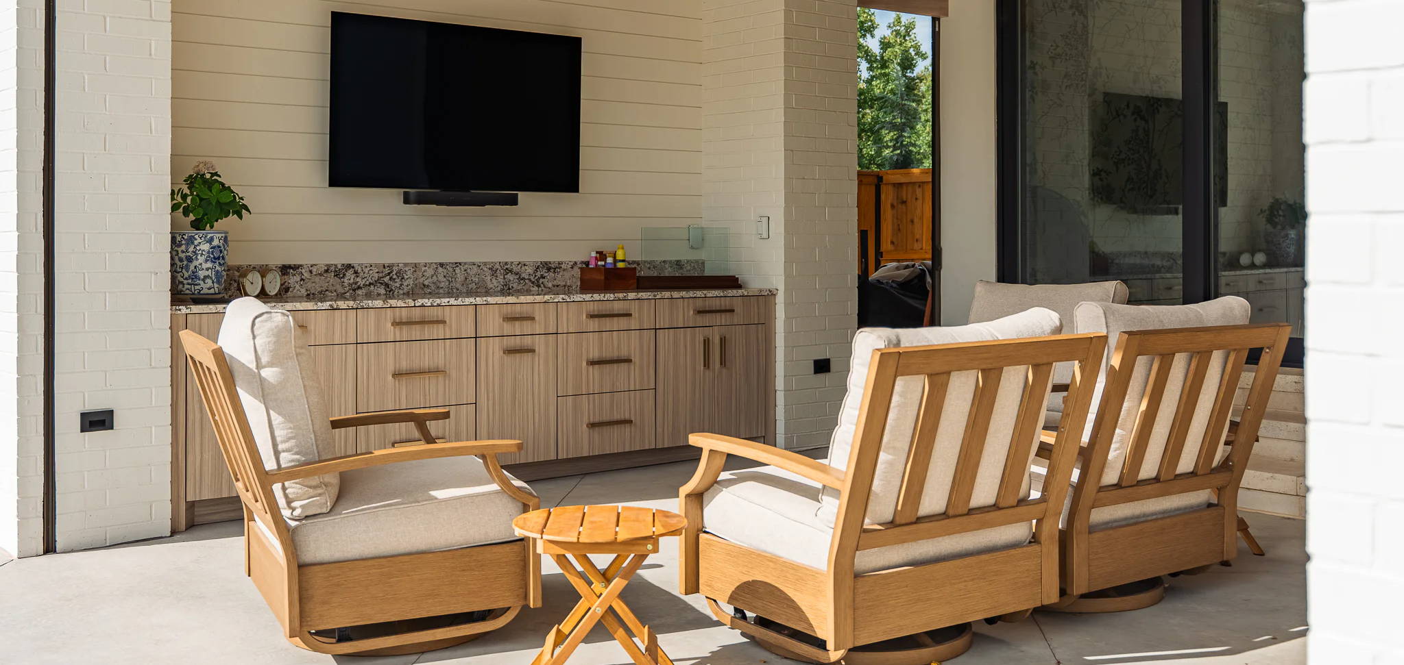 Outdoor seating area with wooden chairs, a table, and a television.