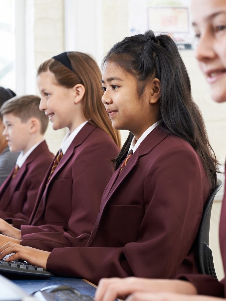 Students in formal school blazers working at computers