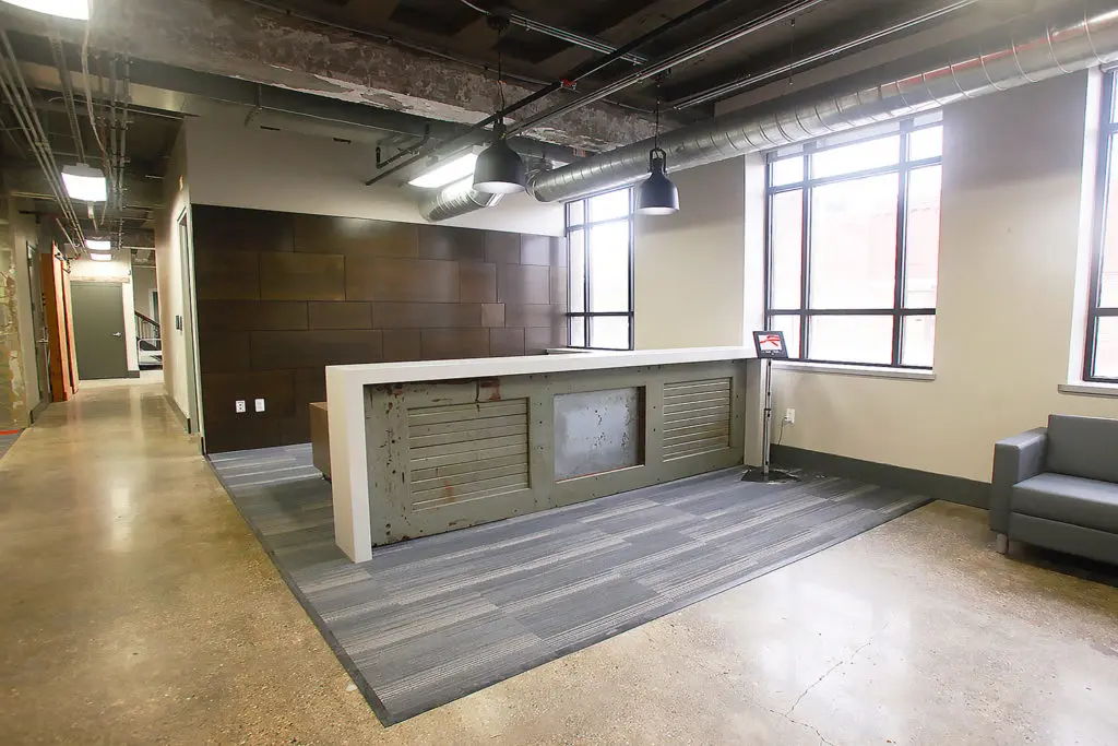 Modern reception area with a desk, seating, and large windows.