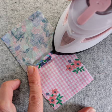 ironing a seam of quilt pieces with a mini iron on a wool pressing mat