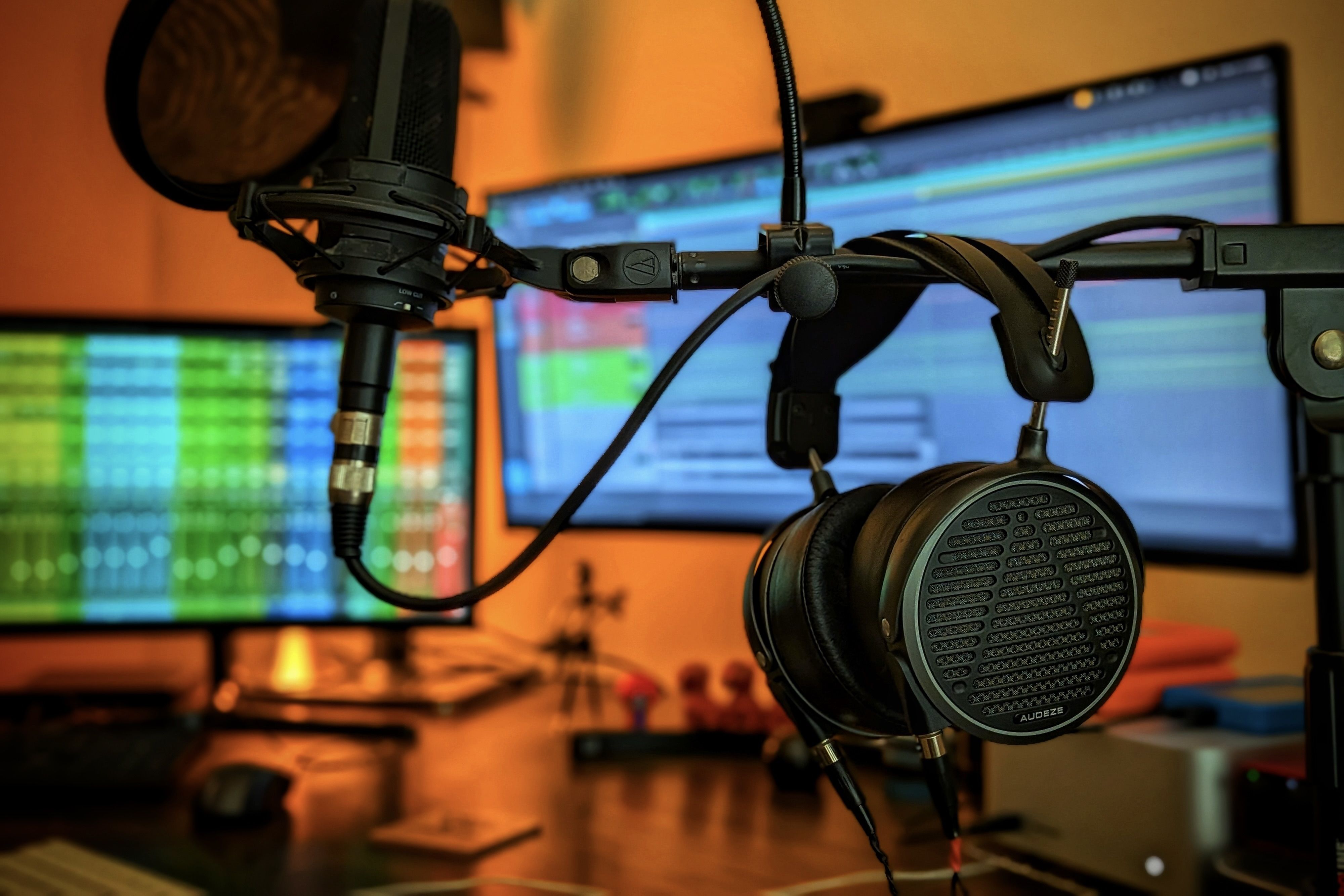 Audeze MM-500 headphones in front of dual monitors with colorful soundwave displays.